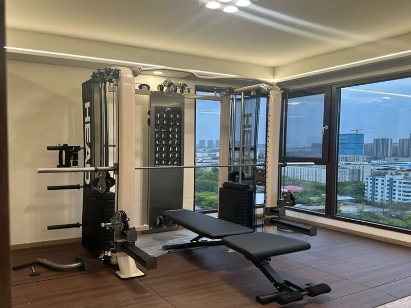 Iemand op zijn knieën die zwarte in elkaar grijpende rubberen sportschooltegels installeert.